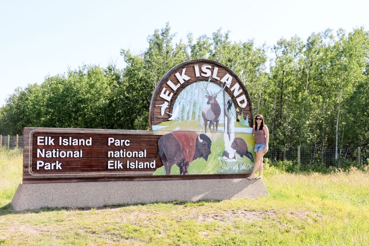 Mitarbeiterin Sarina am Schild des Elk Island Nationalparks