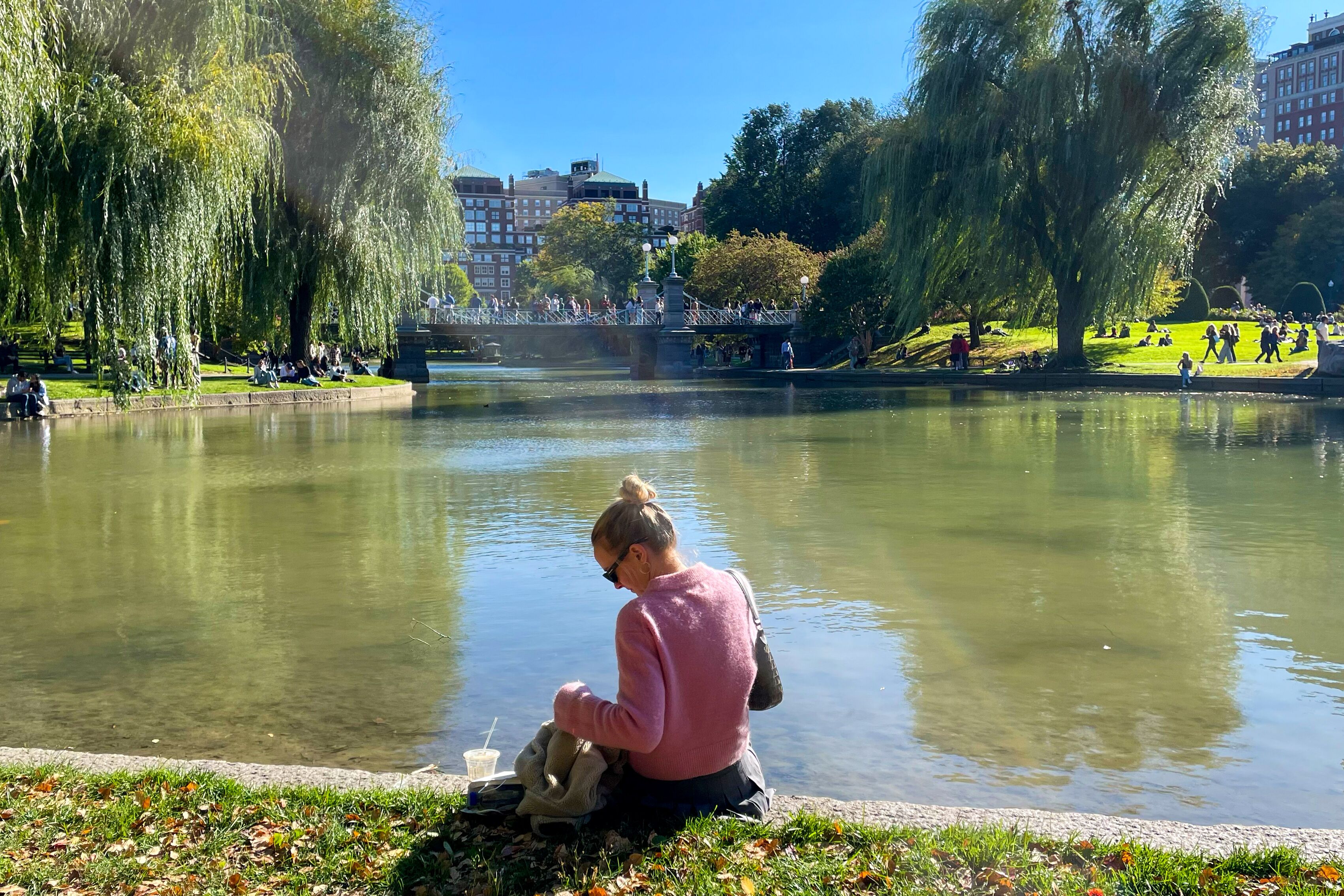 Eine Frau sitzt am Teich im Boston Common
