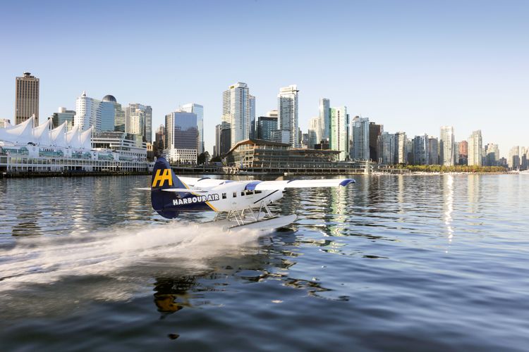 Ein Wasserflugzeug der Harbour Air beim Abflug vor der Skyline von Vancouver