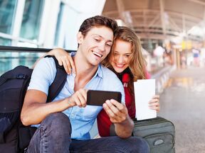 Ein PÃ¤rchen verwendet am Flughafen eine Reise-App auf ihrem Handy