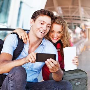 Ein Pärchen verwendet am Flughafen eine Reise-App auf ihrem Handy Ein Pärchen verwendet am Flughafen eine Reise-App auf ihrem Handy
