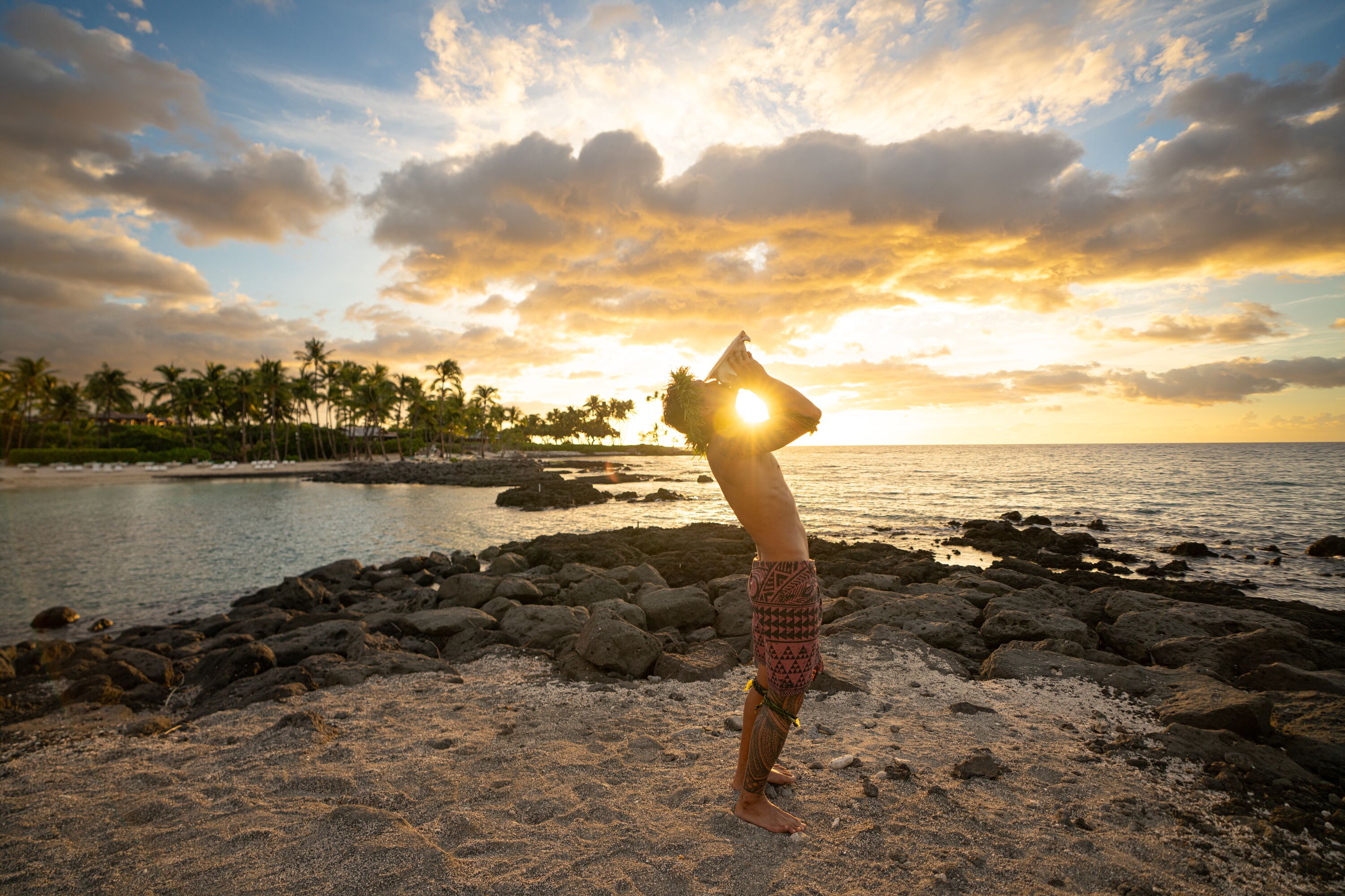 Ein Hawaiianer im Sonnenuntergang am Strand in Fairmont Orchid auf Big Island in Hawaii