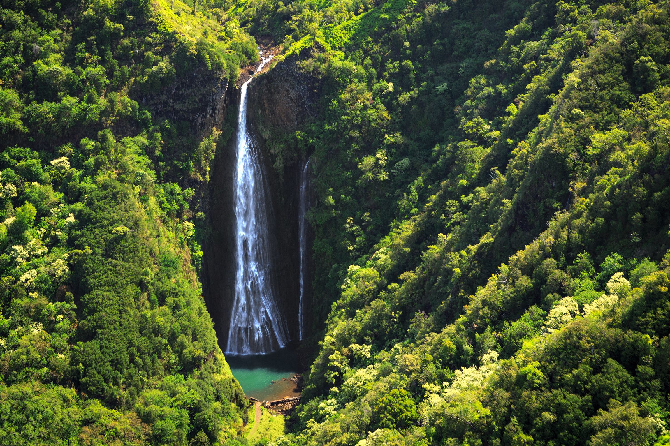 Der Wasserfall Manawaiopuna Falls auf der Insel Kauai auf Hawaii. Ein Wasserfall umgeben von dichter tropischer Vegetation.
