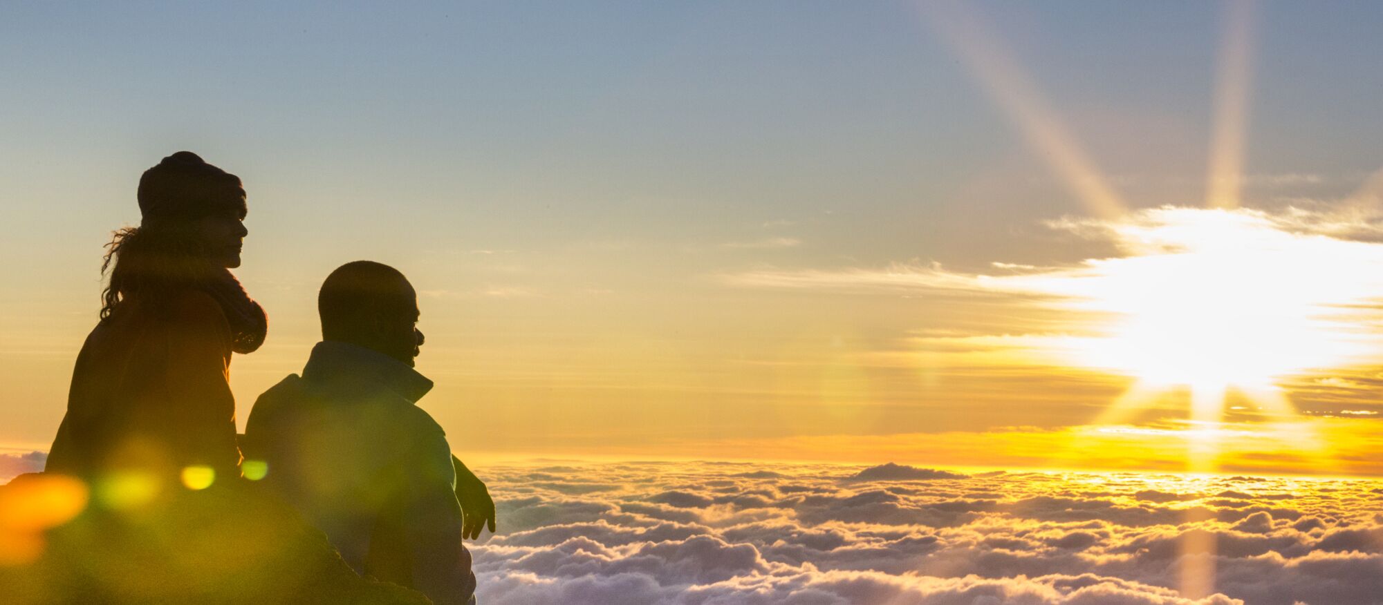 Zwei Personen genießen den Sonnenaufgang im Haleakala National Park.