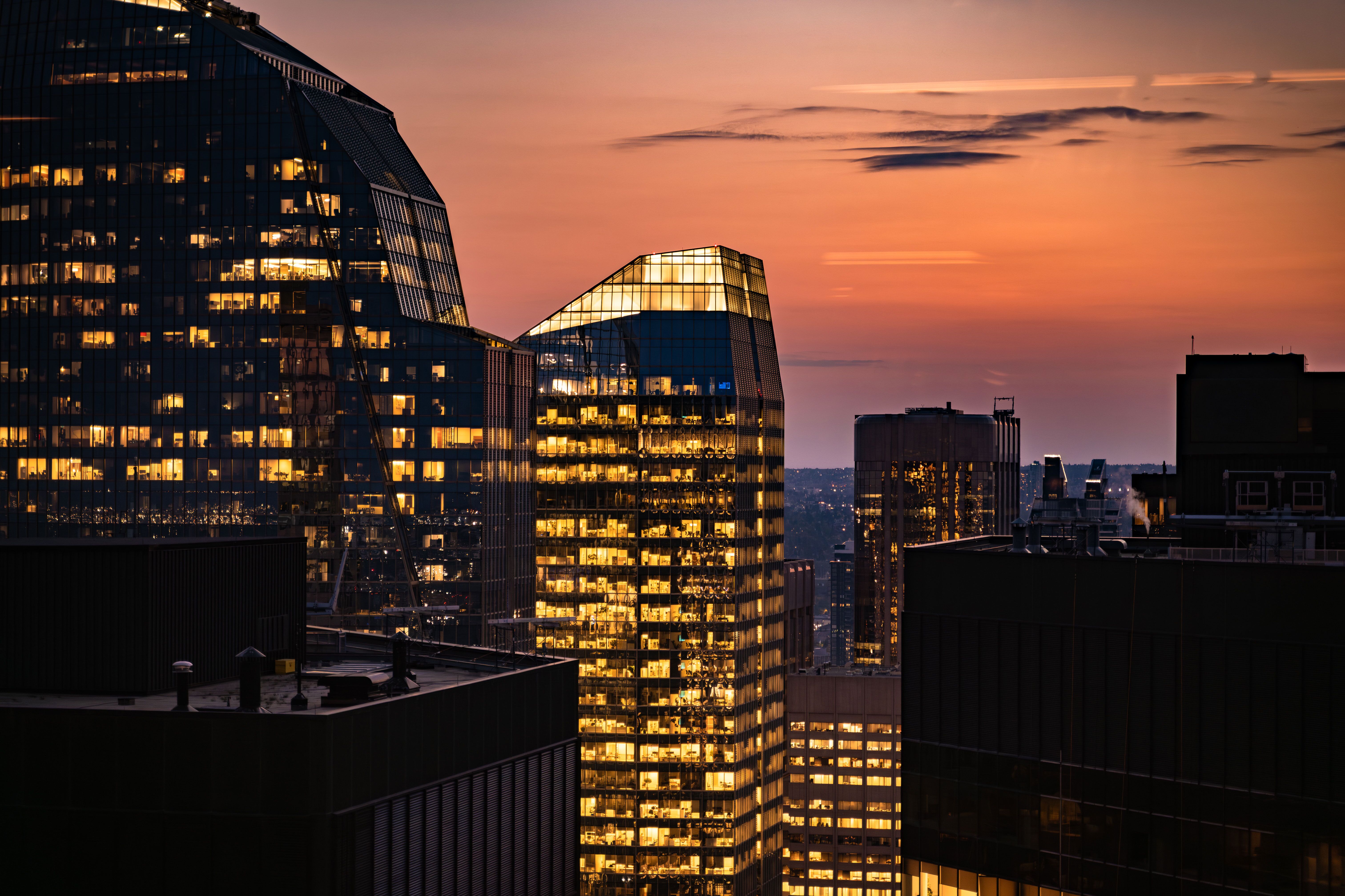 Die markanten Glastürme des Eighth Avenue Place leuchten im warmen Licht der Abenddämmerung über den Dächern der Skyline von Calgary Die markanten Glastürme des Eighth Avenue Place leuchten im warmen Licht der Abenddämmerung über den Dächern der Skyline von Calgary