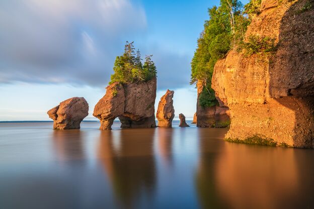Die aufgehende Sonne beleuchtet die Hopewell Rocks bei Flut in New Brunswick