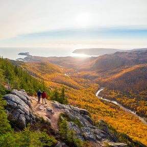 Zwei Wanderer beobachten, wie der Sonnenaufgang den Wald von Nova Scoatia vergoldet