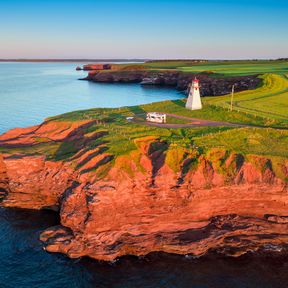 Blick auf das East Point Lighthouse auf Prince Edward Island im Sonnenuntergang mit einem Wohnmobil davor