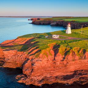 Blick auf das East Point Lighthouse auf Prince Edward Island im Sonnenuntergang mit einem Wohnmobil davor