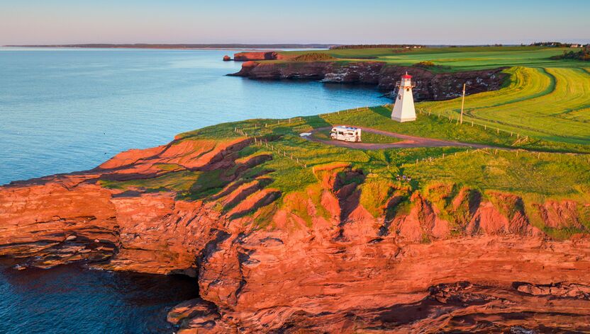 Blick auf das East Point Lighthouse auf Prince Edward Island im Sonnenuntergang mit einem Wohnmobil davor