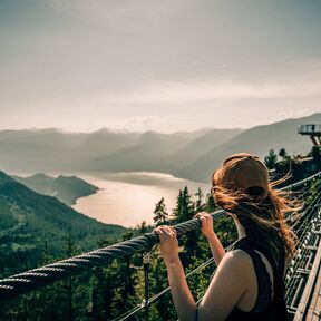 Frau sieht von der Sky Pilot Suspension Bridge aus auf die Landschaft