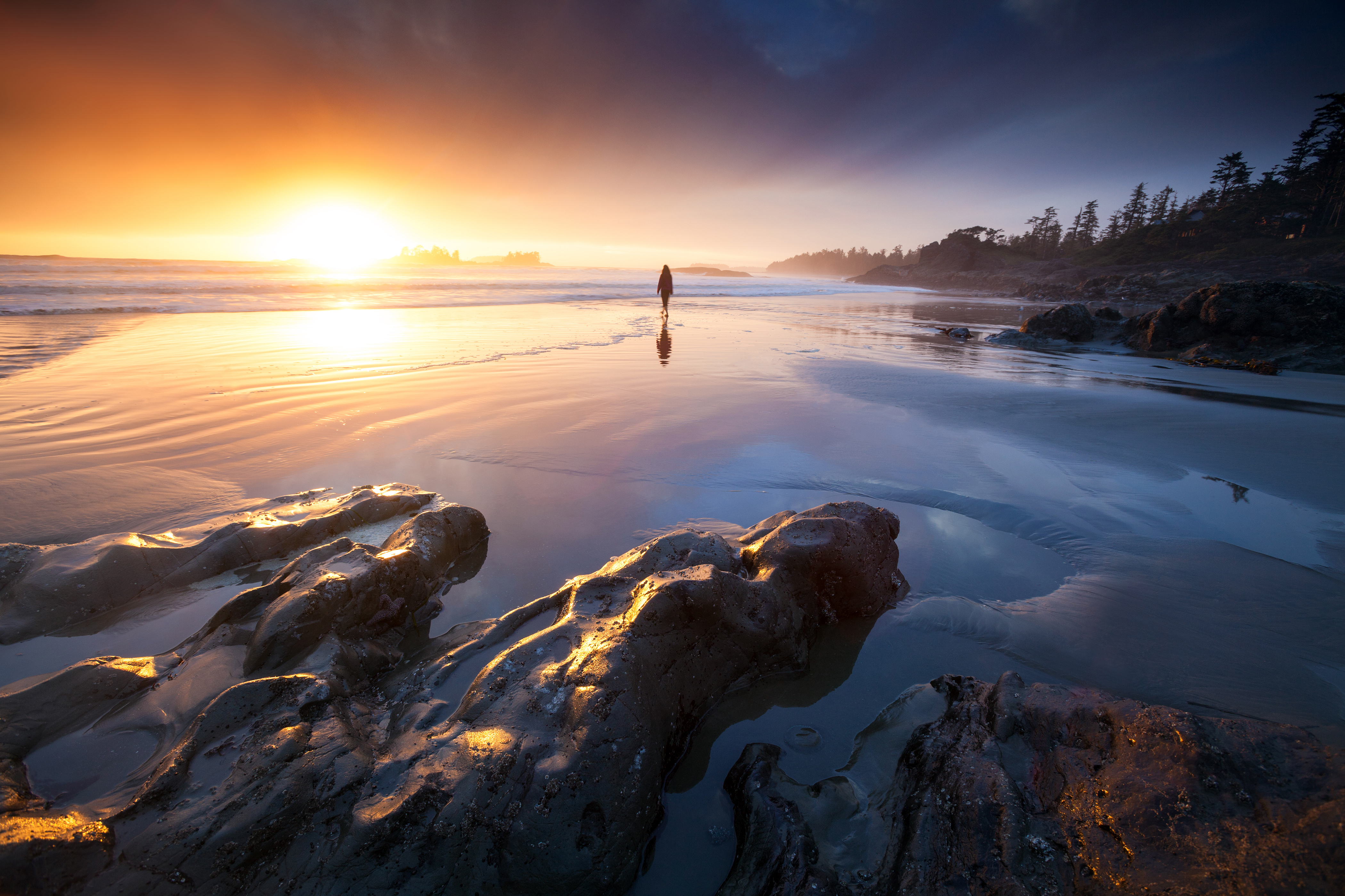 Eine Frau genießt den Sonnenuntergang am Strand bei Tofino in British Columbia
