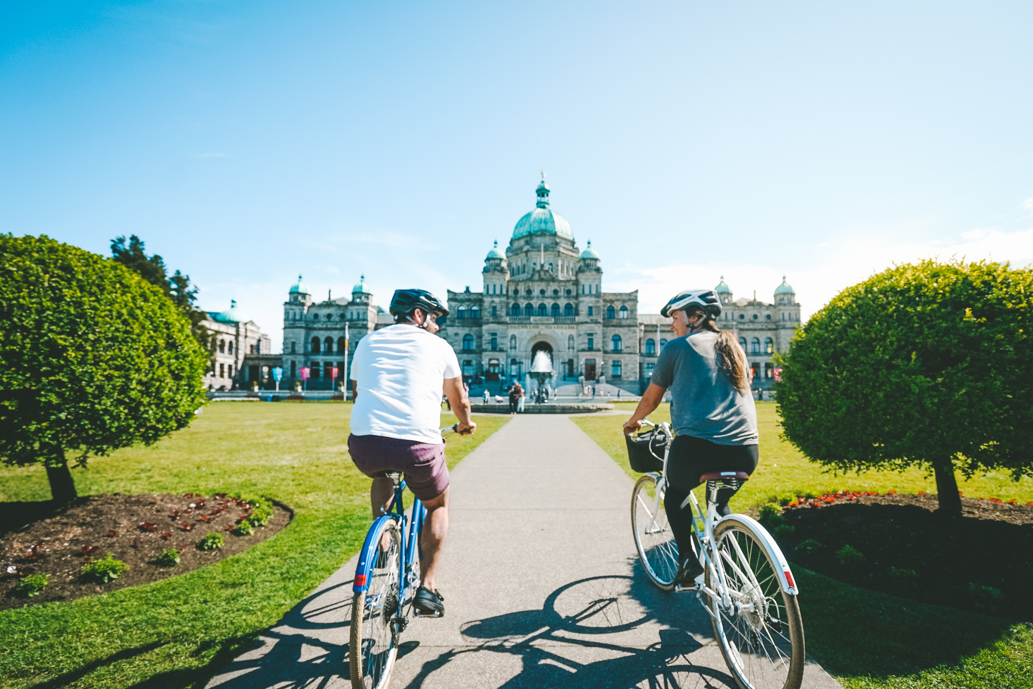 Pärchen fährt Fahrrad vor dem Parlamentsgebäude von British Columbia