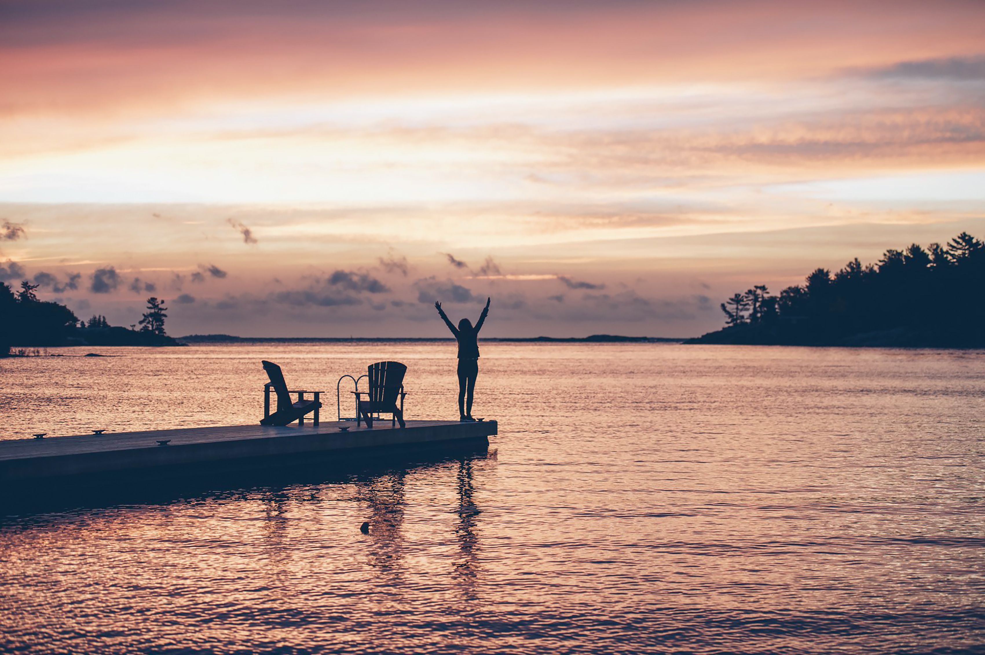 Frau an einem Steg mit hochgestreckten Armen