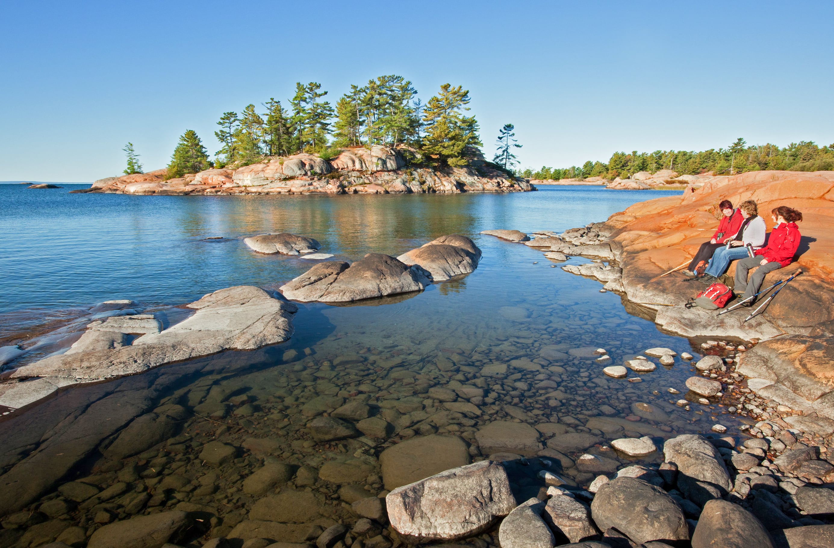 Drei Frauen machen eine Pause beim Wandern im Killarney Provincial Park Drei Frauen machen eine Pause beim Wandern im Killarney Provincial Park
