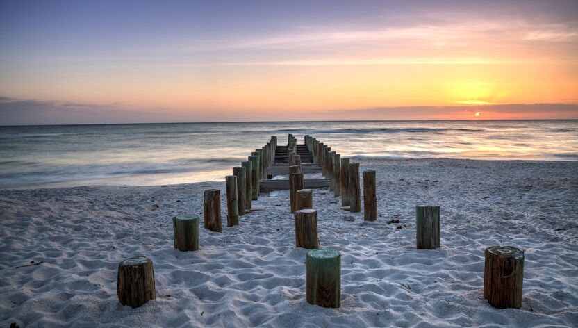 Die Überreste des alten Pier am Strand von Naples bei Sonnenuntergang Die Überreste des alten Pier am Strand von Naples bei Sonnenuntergang