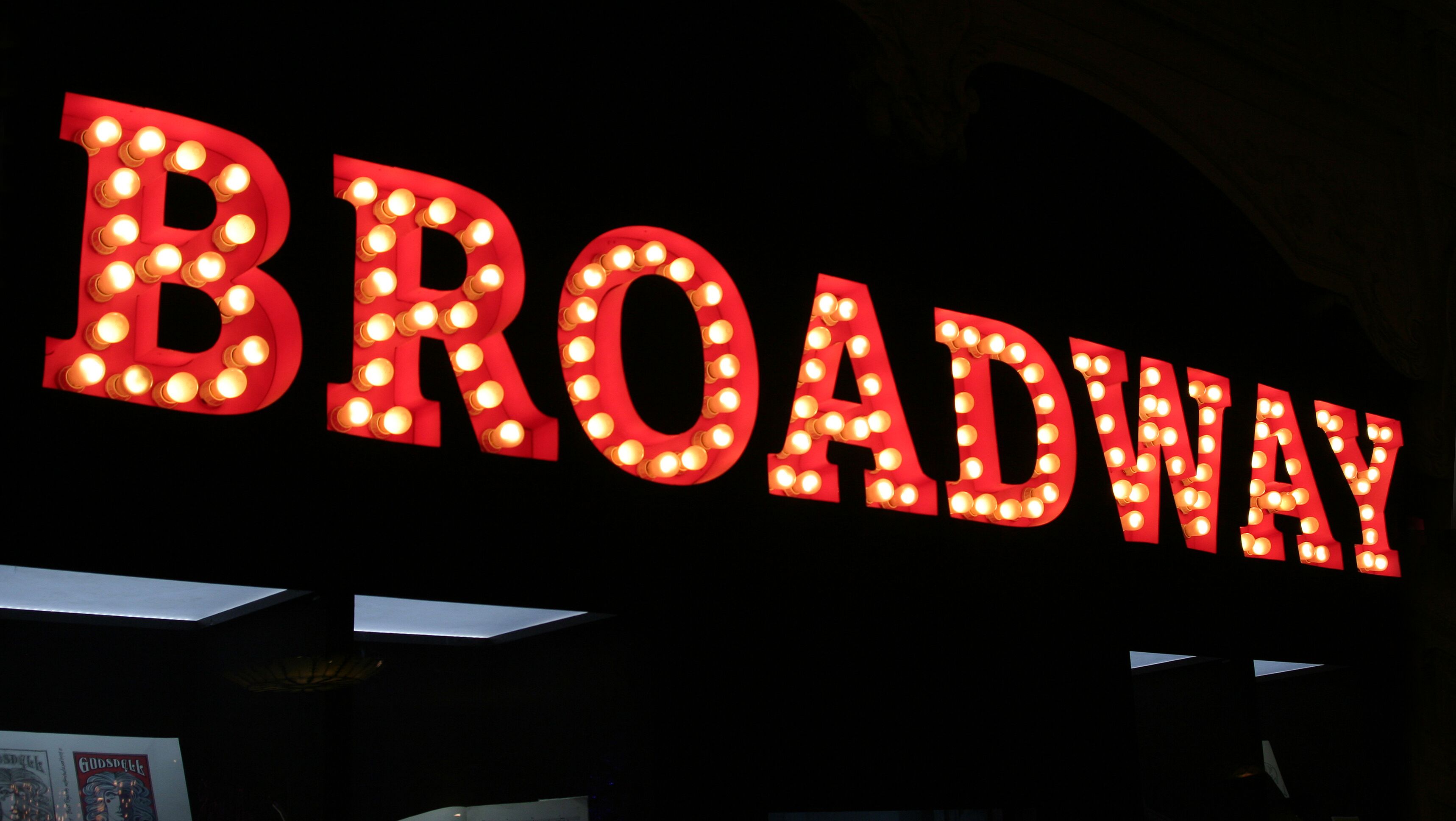Beleuchtetes Broadway-Schild mit großen roten Buchstaben vor einem dunklen Hintergrund.