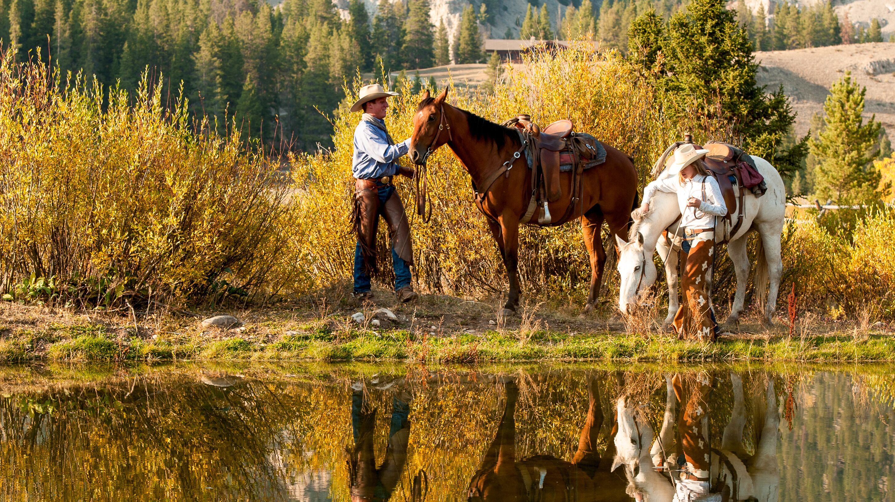 Zwei Pferde und Reiter vor einem See auf der Elkhorn Ranch 
