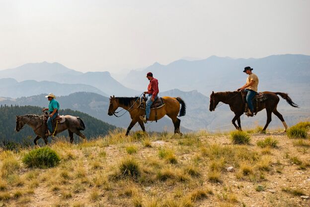 Cowboys reiten durch Berglandschaft in Cody
