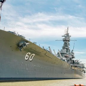 "Battleship Alabama (BB60) photographed at Battleship Memorial Park, Mobile Alabama. Maintenance activity evidenced by cranes was to correct a six-degree list caused by Hurricane Katrina"