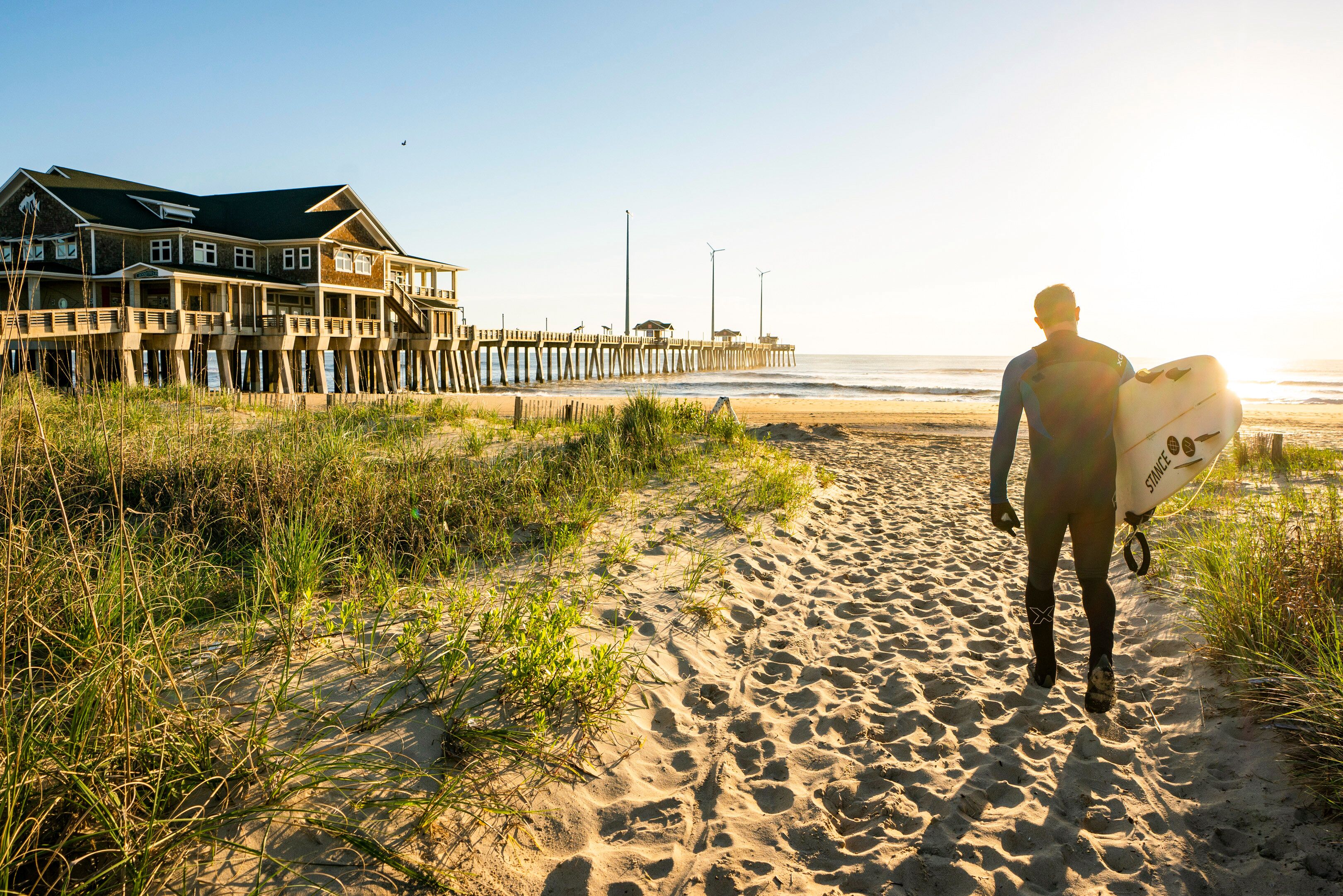 Ein Surfer am Nags Head Pier auf dem Weg zum Meer