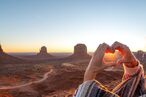 Eine Frau formt ein Herz vor dem Monument Valley