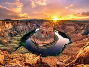 Die aufgehende Sonne beleuchtet das bekannte Horseshoe Bend in Arizona