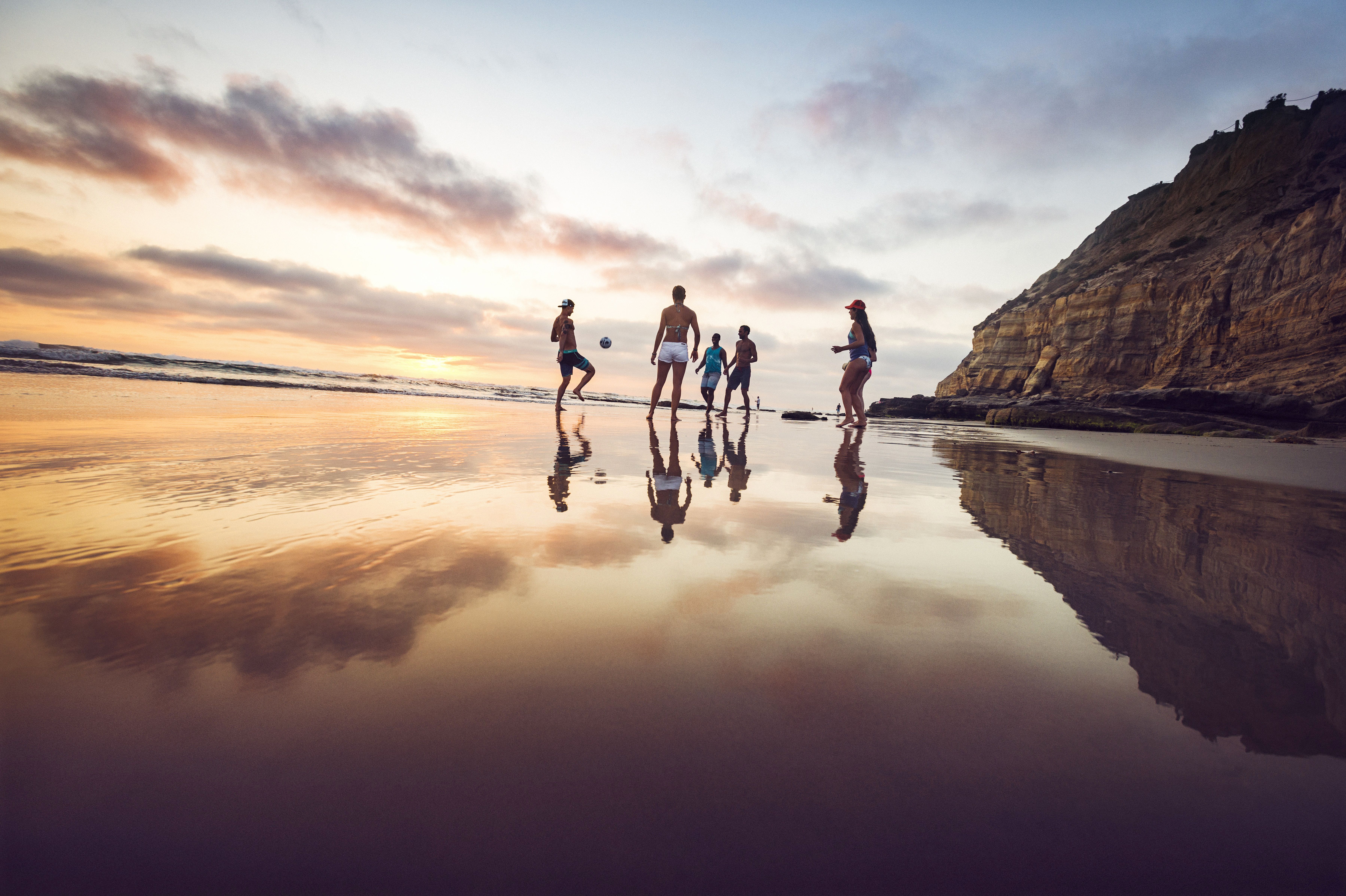 Freunde spielen FuÃŸball am Strand von San Diego