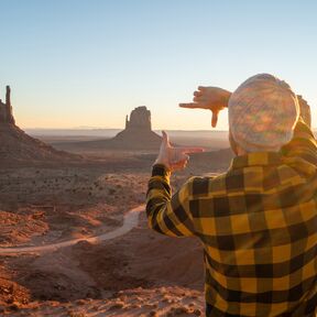 Mann auf einem Felsen im Monument Valley bei Sonnenuntergang