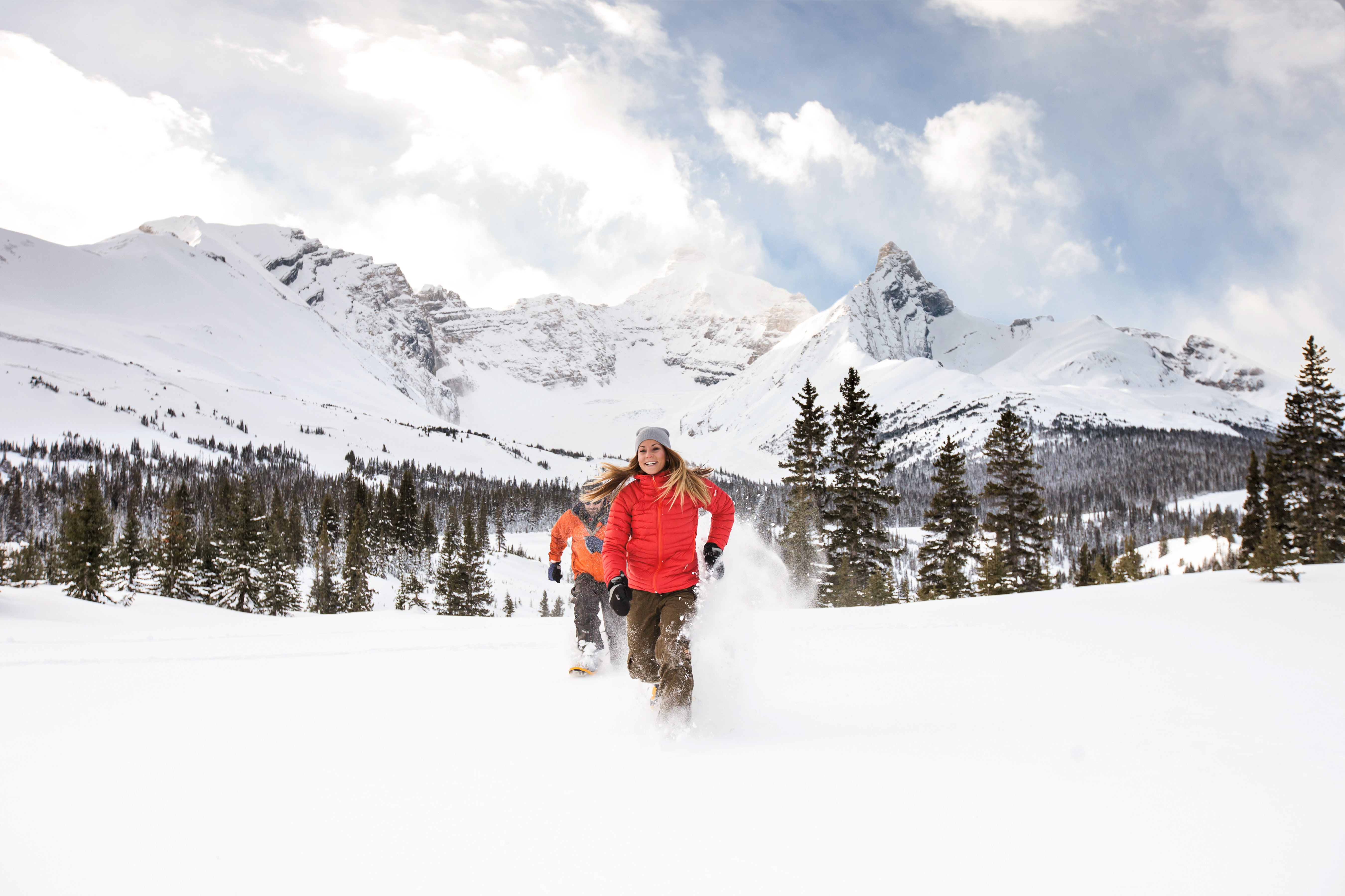 Zwei Personen machen eine Schneeschuwanderung im Winter durch den wunderschönen Powder Schnee in Banff, Kanada.