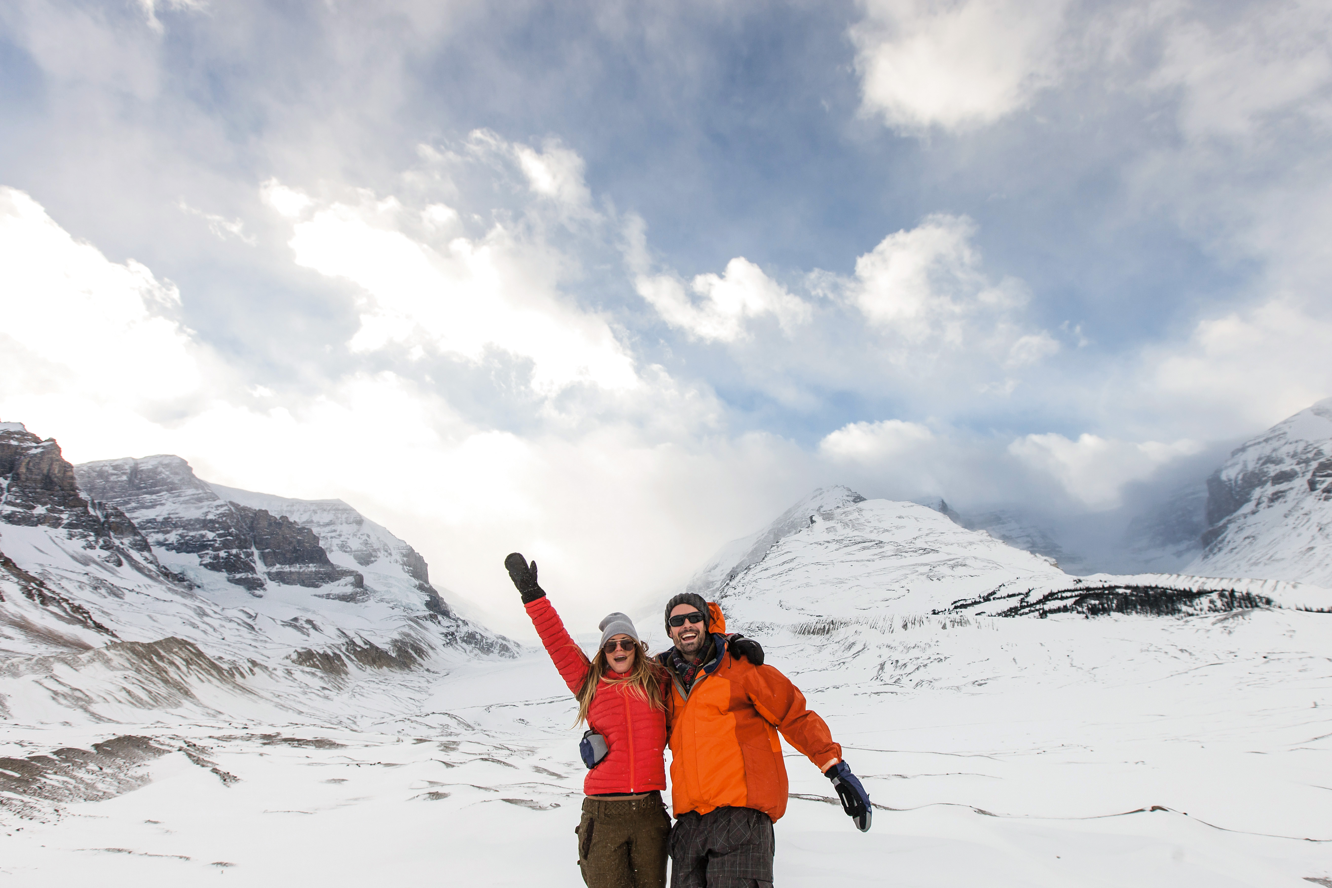 Zwei Personen in Winterkleidung stehen glücklich vor dem Lake Louise im Banff National Park, Alberta