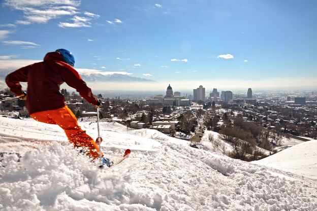 Ein Skifahrer vor der Skyline von Salt Lake City, USA Ein Skifahrer vor der Skyline von Salt Lake City, USA